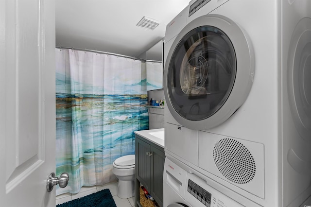 bathroom with visible vents, toilet, vanity, stacked washing maching and dryer, and tile patterned floors