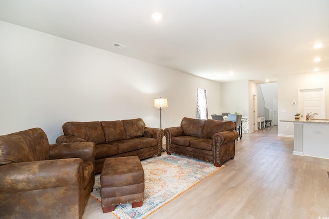 living area featuring baseboards, light wood finished floors, visible vents, and recessed lighting