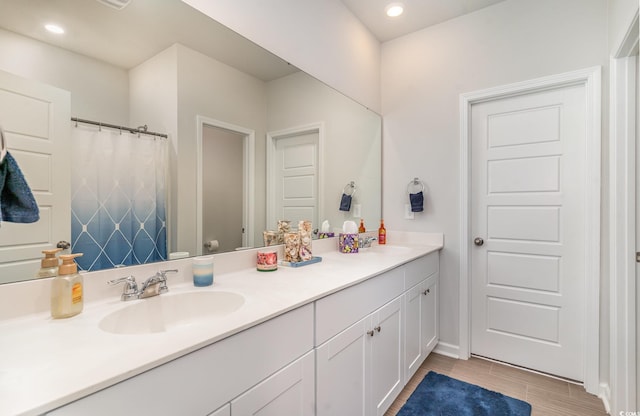 bathroom featuring double vanity, a sink, and recessed lighting