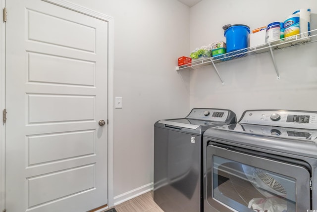 laundry area featuring light wood-type flooring, laundry area, washing machine and dryer, and baseboards