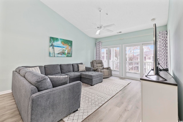 living area with vaulted ceiling, baseboards, light wood-style flooring, and a ceiling fan