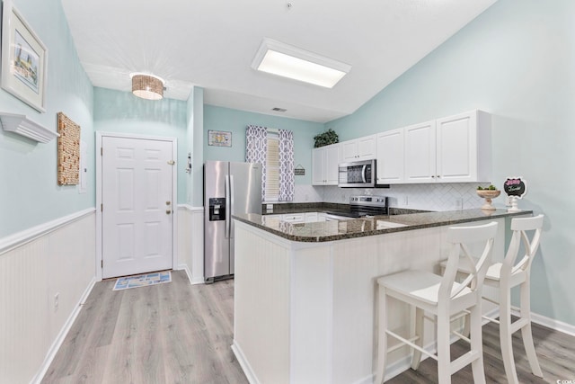 601 N Hillside Dr Unit 4632, North Myrtle Beach, SC 29582 - kitchen with stainless steel appliances, light wood-style flooring, dark stone countertops, backsplash, and vaulted ceiling