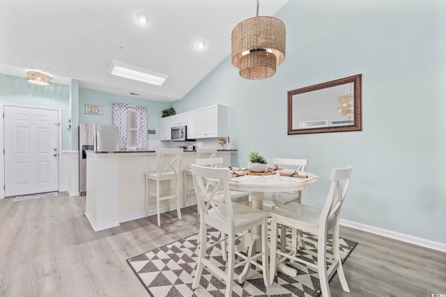 dining space featuring high vaulted ceiling, recessed lighting, light wood-style flooring, and baseboards