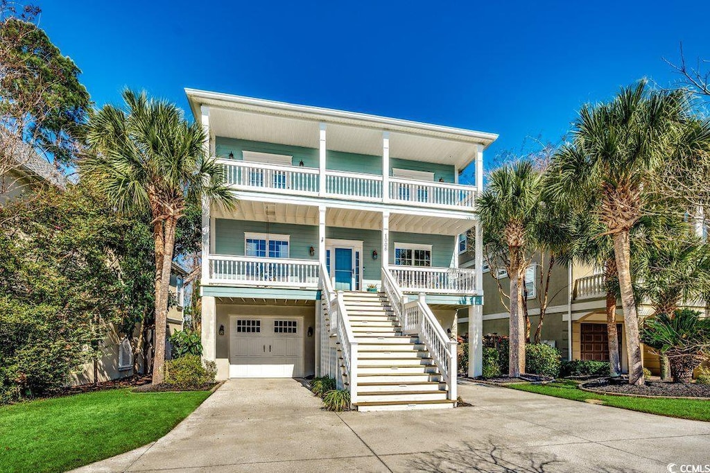 1006 Clubhouse Dr, North Myrtle Beach, SC 29582 - coastal home featuring an attached garage, a balcony, covered porch, driveway, and stairway