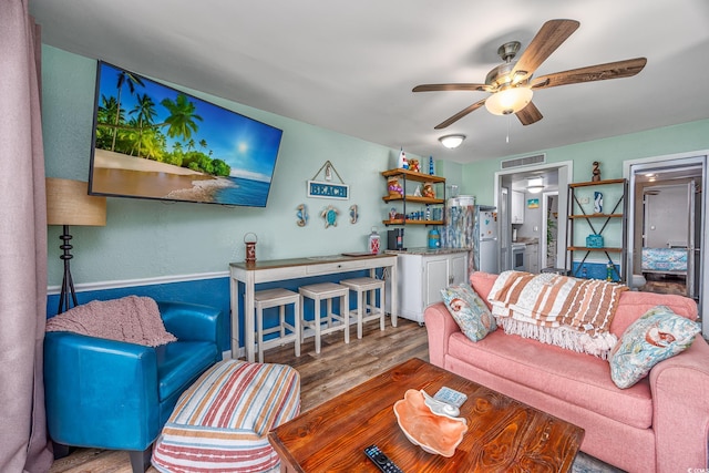 living room with ceiling fan, wood finished floors, and visible vents