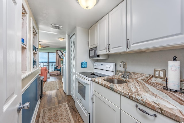 kitchen with white electric range oven, black microwave, visible vents, white cabinetry, and a sink