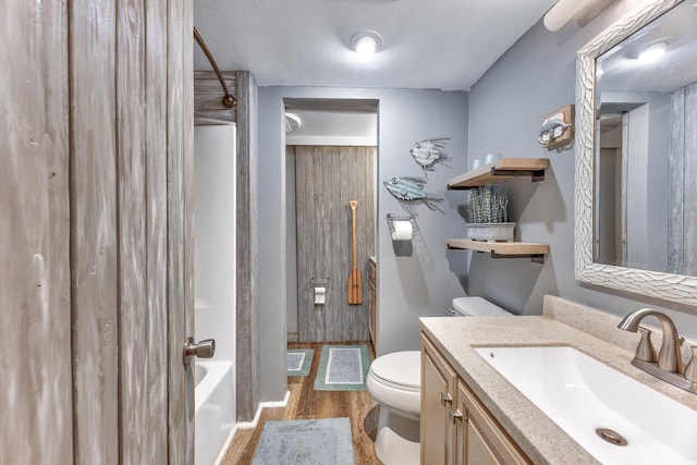 bathroom featuring shower / bathtub combination, vanity, wood finished floors, and toilet