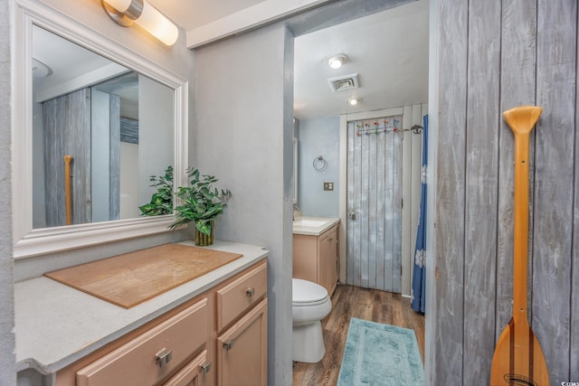 full bath with toilet, visible vents, wood finished floors, and vanity