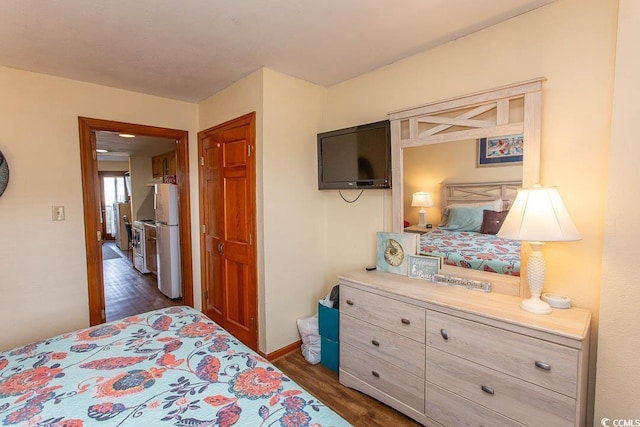 bedroom with dark wood-style flooring, freestanding refrigerator, and baseboards