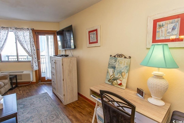 interior space with a wall mounted air conditioner, wood finished floors, and baseboards