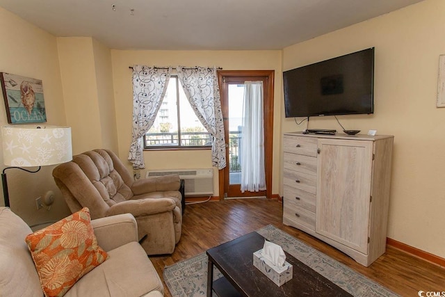 living room with an AC wall unit, baseboards, and wood finished floors