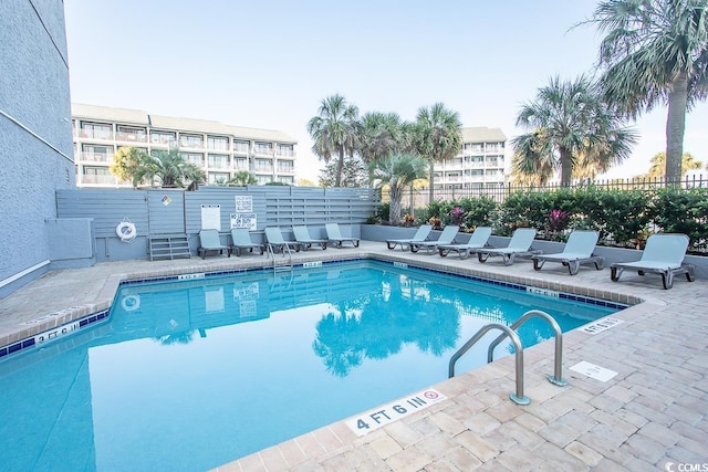 community pool with a patio area and fence