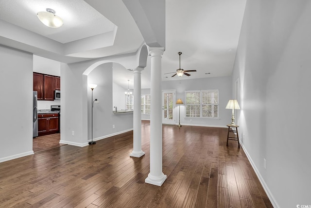 living area featuring arched walkways, dark wood-style flooring, decorative columns, baseboards, and ceiling fan with notable chandelier