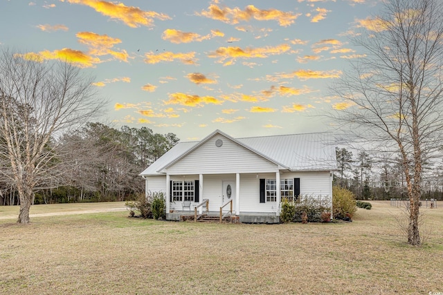 view of front facade featuring a front yard, covered porch, and metal roof