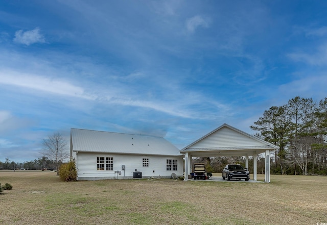 back of property with central AC, metal roof, and a lawn