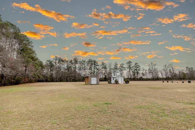 yard at dusk with an outdoor structure, a detached garage, and a storage shed