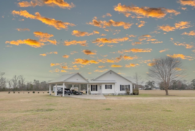 back of house with an attached carport, a patio area, and a yard