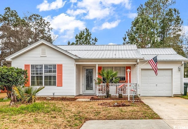 ranch-style home with a garage, concrete driveway, covered porch, and metal roof