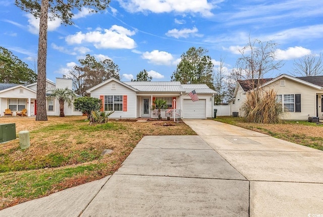 ranch-style house featuring covered porch, concrete driveway, an attached garage, a front yard, and metal roof