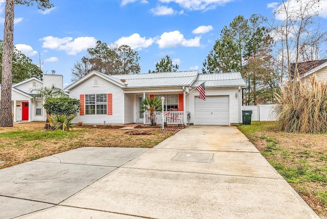 ranch-style house featuring concrete driveway, an attached garage, metal roof, fence, and covered porch