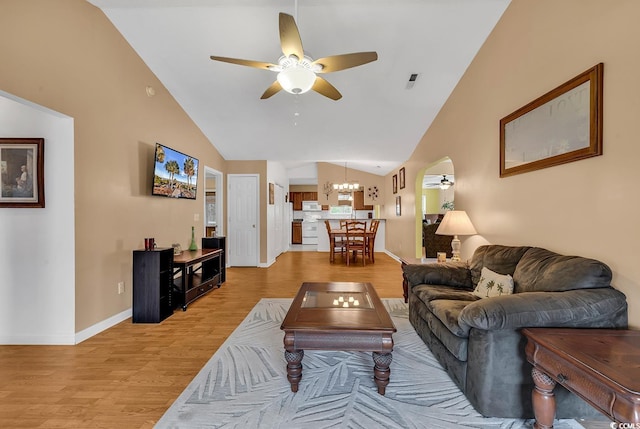 living area featuring light wood-style flooring, high vaulted ceiling, baseboards, and ceiling fan with notable chandelier