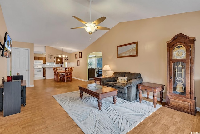 living room with ceiling fan with notable chandelier, arched walkways, light wood-type flooring, lofted ceiling, and baseboards