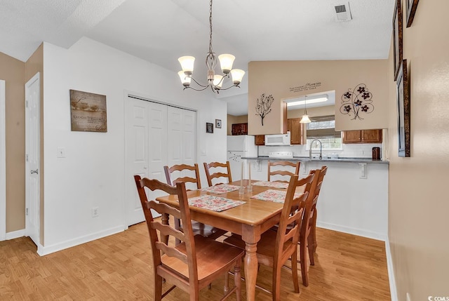 dining area with baseboards, a notable chandelier, vaulted ceiling, and light wood finished floors