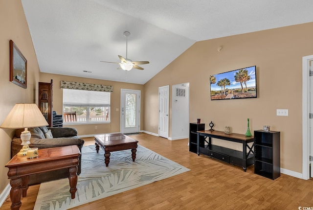 living area featuring lofted ceiling, light wood-type flooring, and baseboards