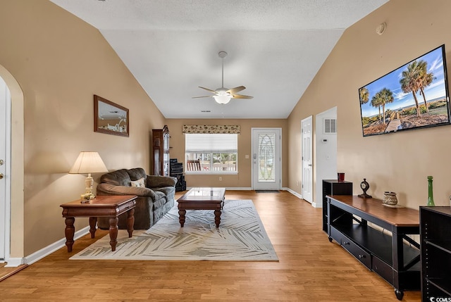 living room with light wood-style floors, ceiling fan, arched walkways, visible vents, and baseboards