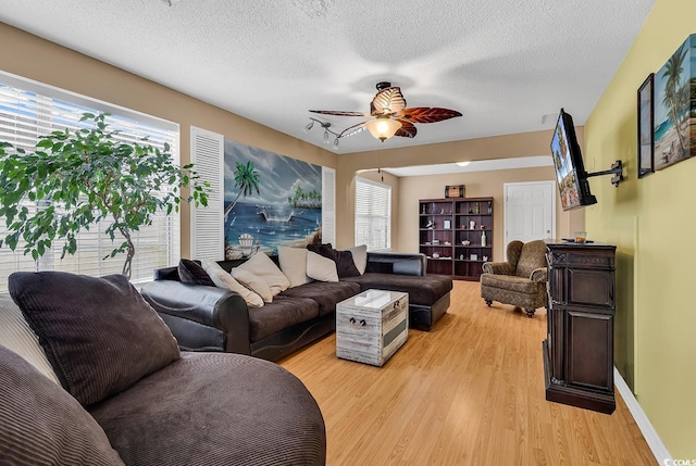 living area featuring ceiling fan, plenty of natural light, a textured ceiling, and wood finished floors