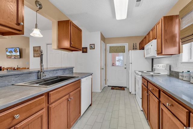 kitchen featuring brown cabinetry, white appliances, a sink, and decorative backsplash