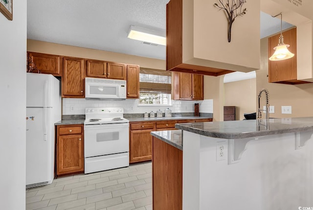 kitchen featuring brown cabinetry, white appliances, a peninsula, and a breakfast bar area