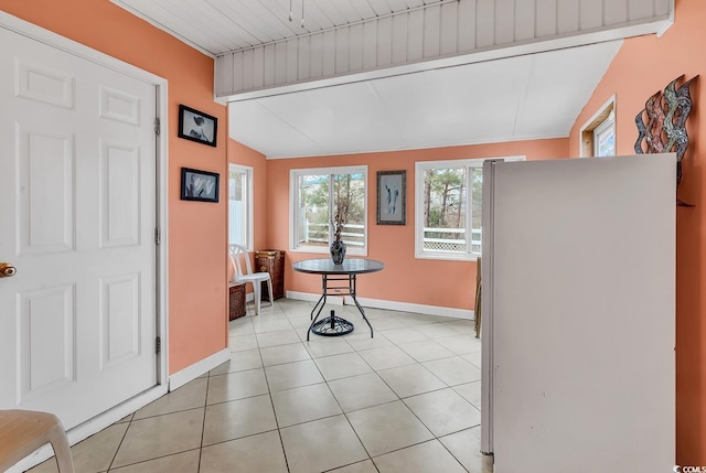 dining area featuring light tile patterned floors, vaulted ceiling, and baseboards