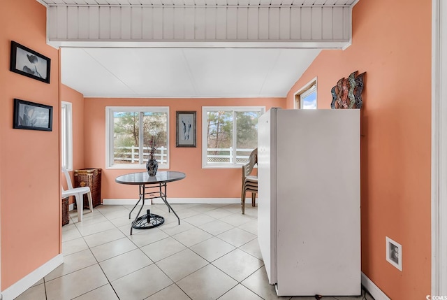 dining space with light tile patterned floors, plenty of natural light, and lofted ceiling with beams