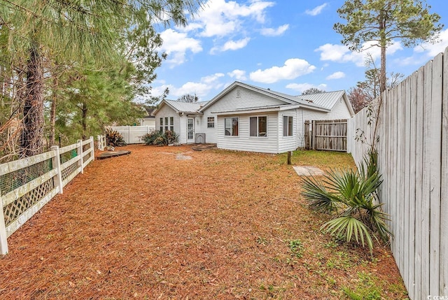 rear view of house featuring metal roof and a fenced backyard