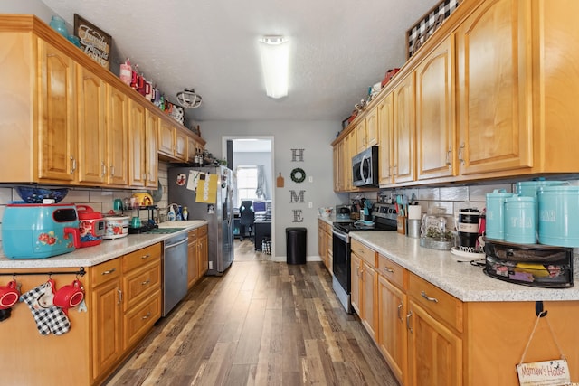 kitchen featuring light countertops, backsplash, appliances with stainless steel finishes, wood finished floors, and baseboards