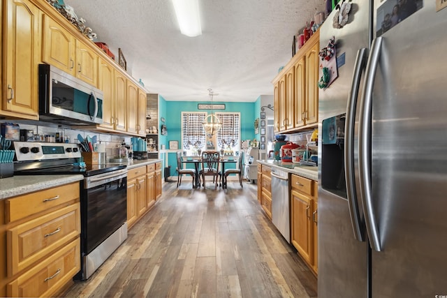 kitchen featuring a textured ceiling, stainless steel appliances, hardwood / wood-style floors, and light countertops