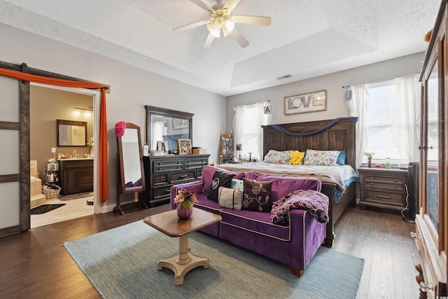 bedroom featuring a raised ceiling, visible vents, wood-type flooring, a textured ceiling, and baseboards