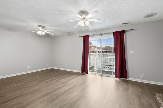 spare room featuring baseboards, ceiling fan, visible vents, and wood finished floors