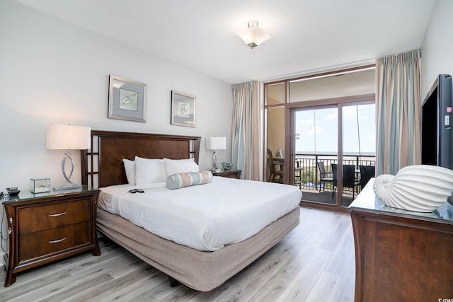 bedroom featuring light wood-type flooring, access to outside, and floor to ceiling windows