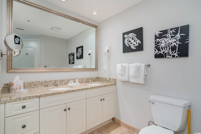 bathroom featuring toilet, double vanity, visible vents, and a sink