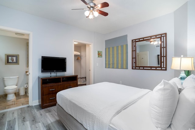 bedroom with light wood finished floors, baseboards, connected bathroom, ceiling fan, and a spacious closet