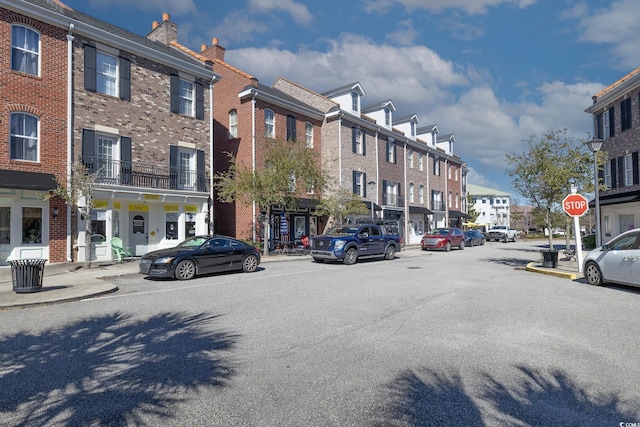 view of street with sidewalks, curbs, a residential view, street lighting, and traffic signs