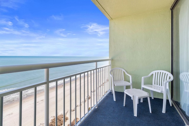 balcony with a water view and a view of the beach