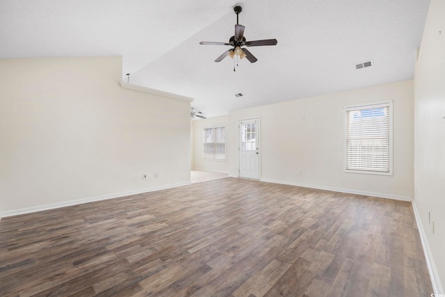 empty room featuring lofted ceiling, wood finished floors, visible vents, a ceiling fan, and baseboards