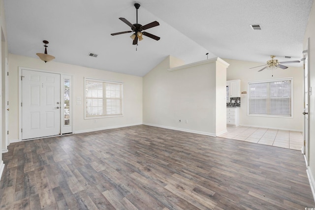 unfurnished living room with lofted ceiling, a ceiling fan, visible vents, and wood finished floors