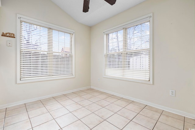 spare room featuring vaulted ceiling, a textured ceiling, a ceiling fan, and baseboards