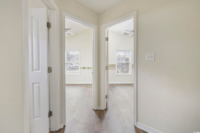 hall featuring lofted ceiling, wood finished floors, and baseboards