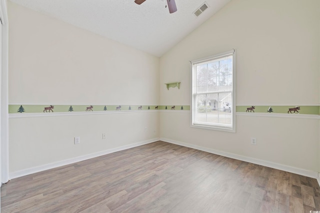 unfurnished room featuring light wood-style flooring, visible vents, vaulted ceiling, and a ceiling fan