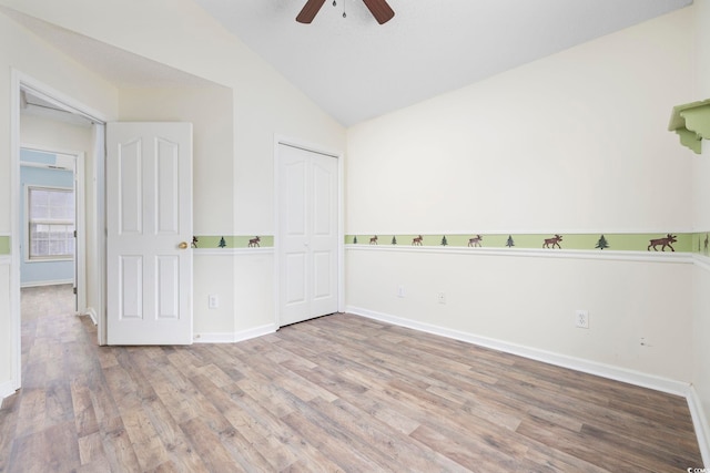 spare room with lofted ceiling, light wood finished floors, a ceiling fan, and baseboards